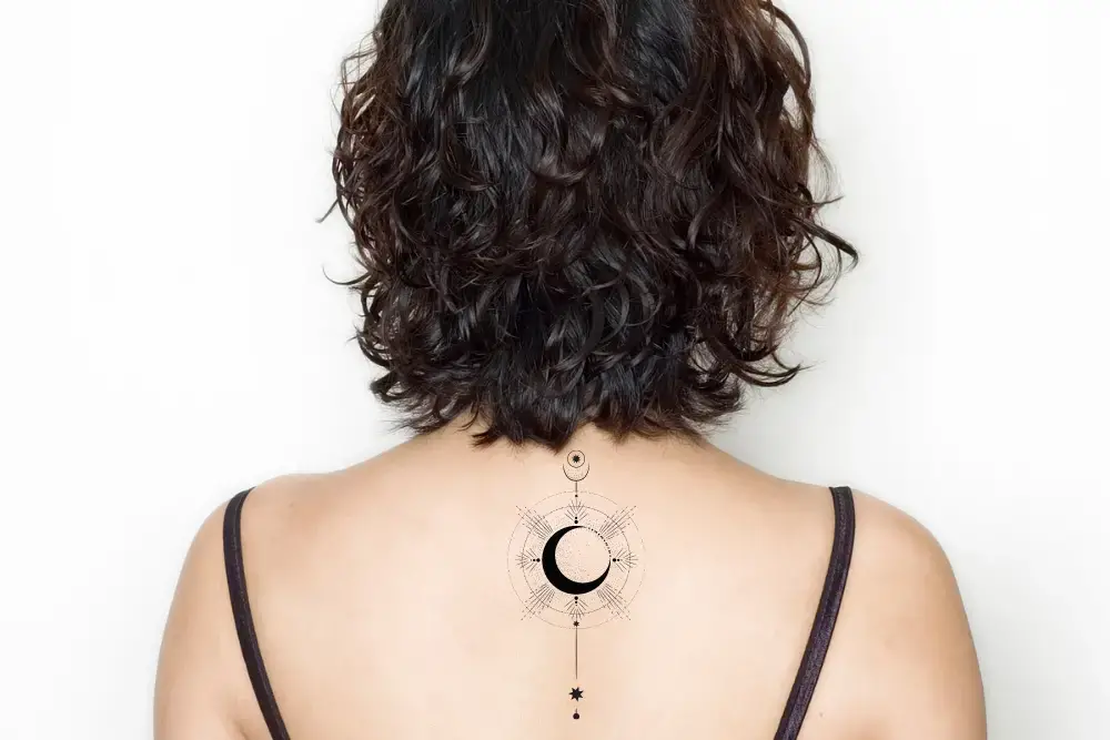 Woman's back with stylish moon tattoo